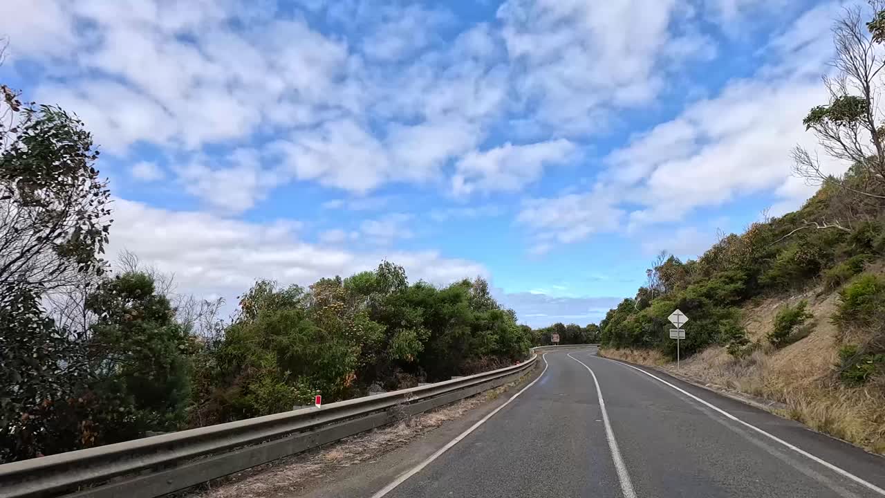A 14-second video captures a serene drive along the winding Great Ocean Road, surrounded by lush greenery and clear blue skies