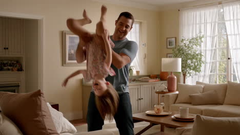 father and daughter playing happily upside down in a living room