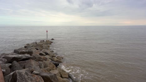 rocky breakwater and warning marker post on the sea shore of sidmouth in devon, england