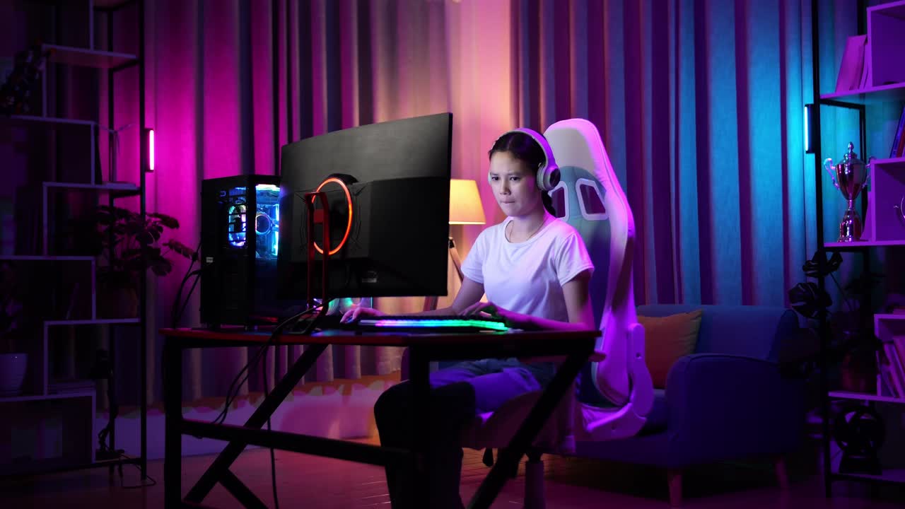 una adolescente asiática seria jugando videojuegos en la computadora