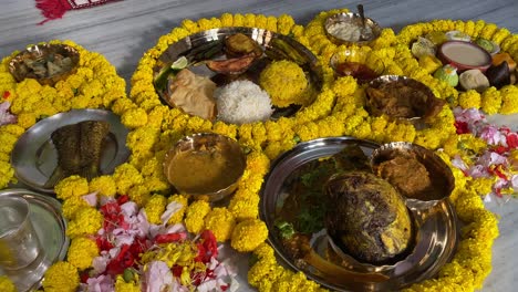 Top-down-shot-over-traditional-bengali-cuisine-dish-for-Aiburobhat-lunch-beautifully-decorated-with-yellow-flowers-inside-a-wedding-hall