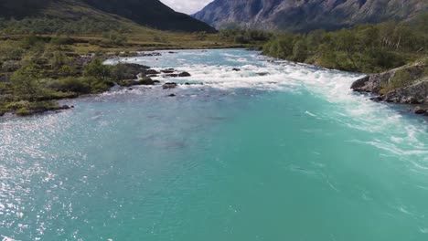 aerial view of a turquoise river flowing between lush green mountains