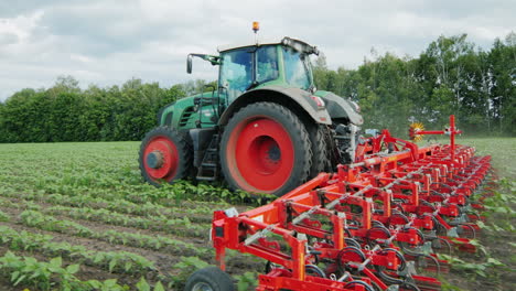 tractor pulls field cultivator cutting weeds