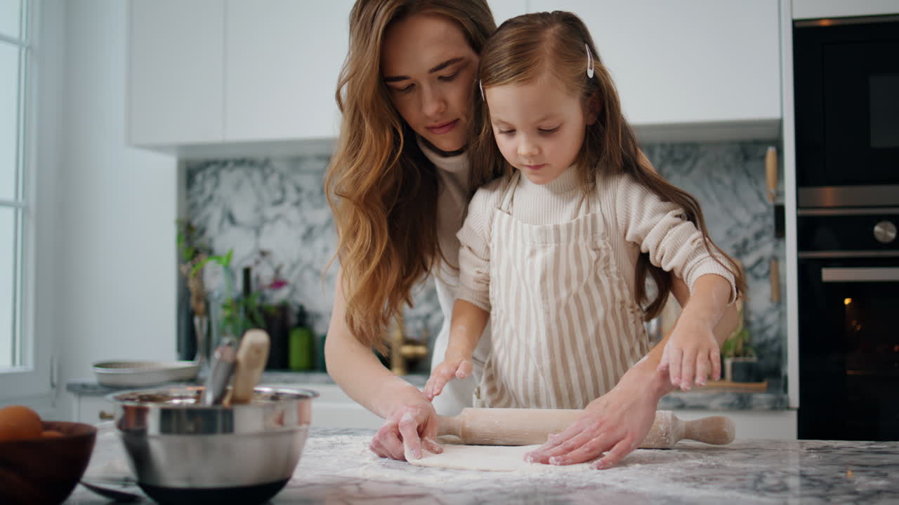 가족이 집에서 반죽을 만드는 데 참여했습니다. 친절한 어머니가 아이를 돕습니다.