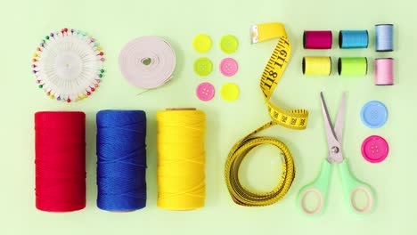 knitting and sewing materials ordering on green background. stop motion flay lay