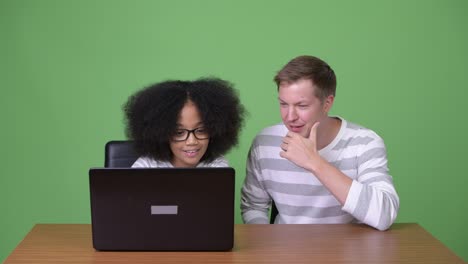 una joven africana y un joven escandinavo usando una computadora portátil juntos