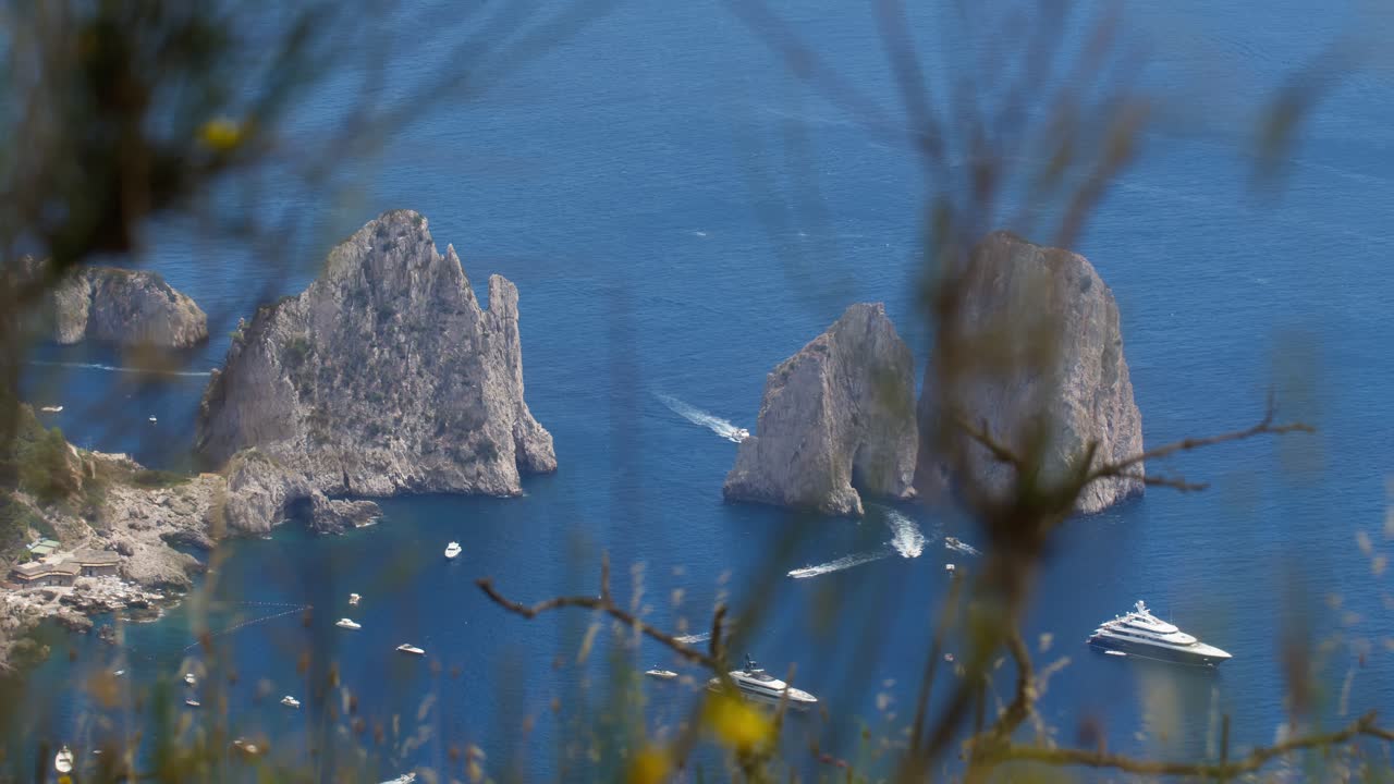 Static close-up of Faraglioni rocks with luxury boats on the crystal-clear sea