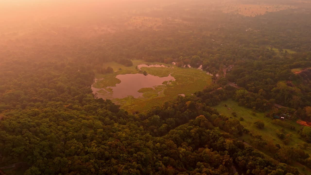 A stunning aerial clip of Sigiriya Rock at sunrise, surrounded by lush jungle and a serene lake reflecting the morning light.