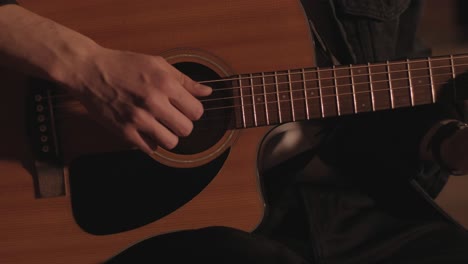 a handsome guy plays an acoustic guitar in an abandoned cinema. the musician sings a song and accompanies on the guitar