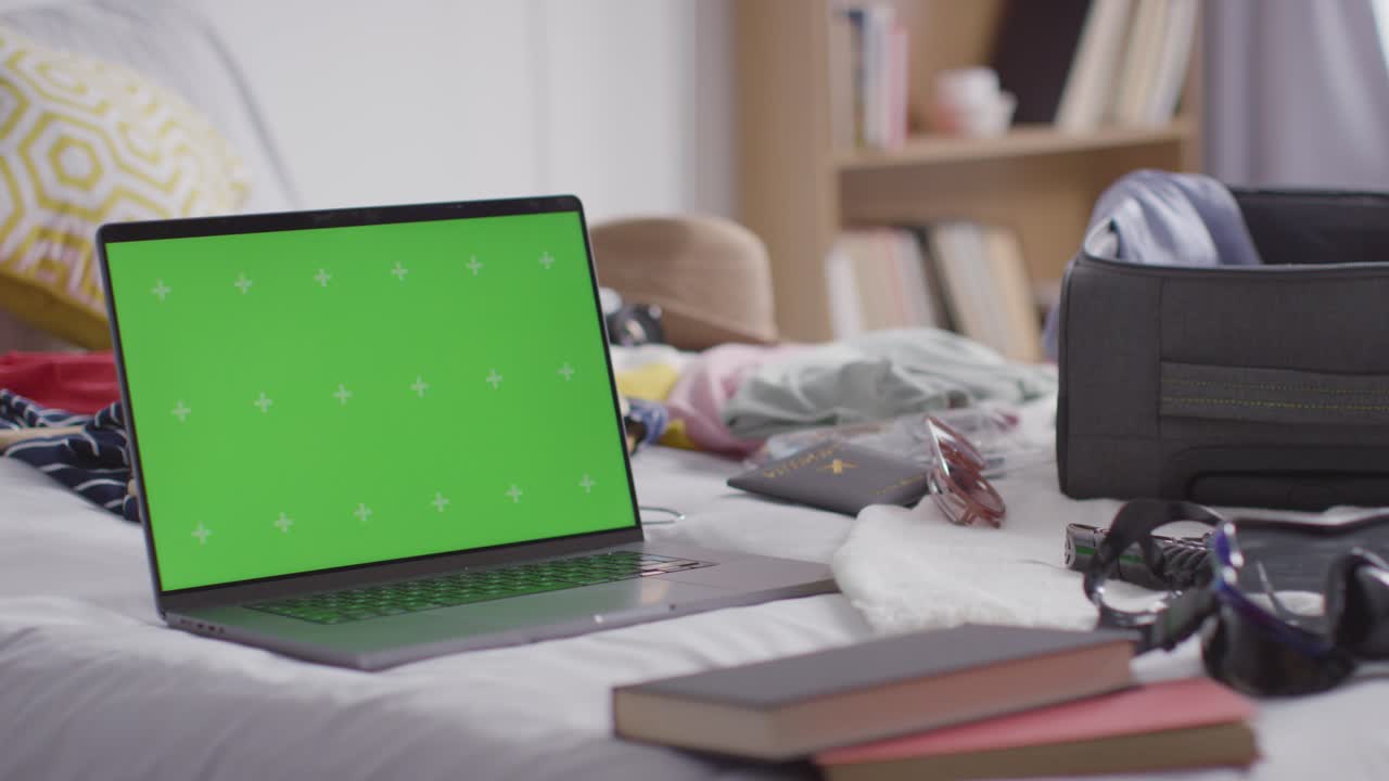 portátil de pantalla verde con maleta abierta en la cama en casa siendo empacado para las vacaciones de verano 1