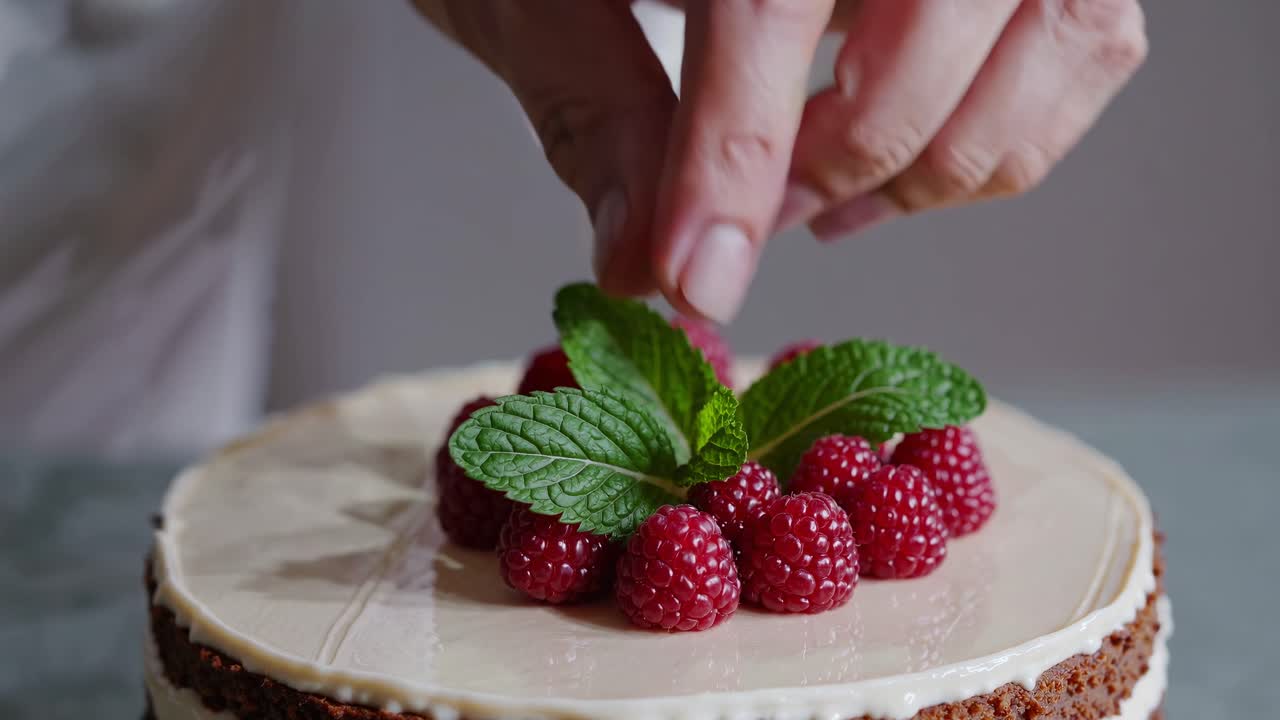 Chef Decorating Cake with Fresh Raspberries and Mint Leaves