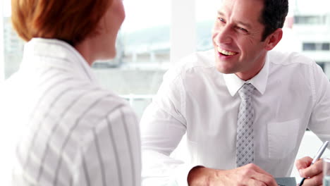 Handsome-businessman-talking-with-colleague-at-desk