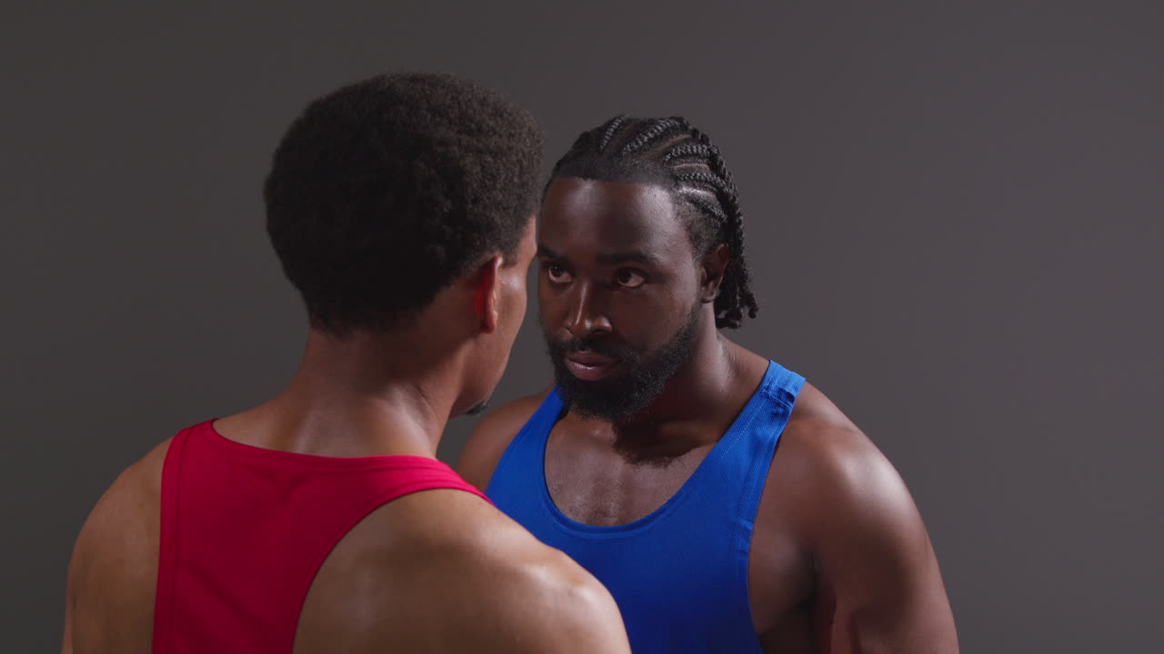 남자 권투 선수와 상대 선수가 권투 경기 전에 얼굴을 마주보고 서로를 쳐다보고 있습니다.