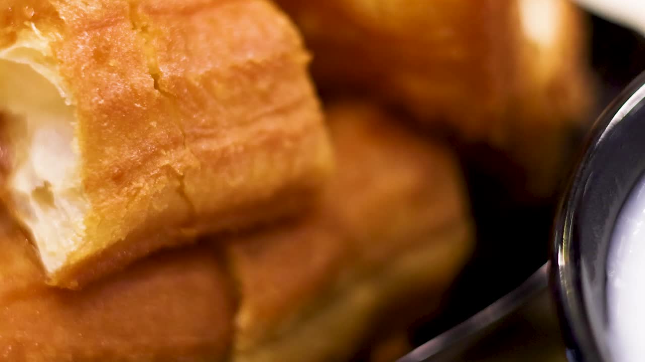 A detailed view of crispy dough sticks paired with a creamy bowl of congee.