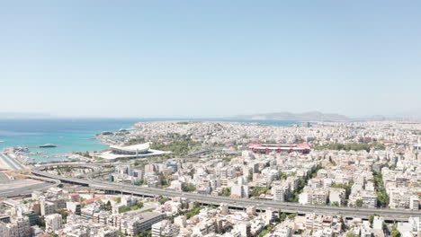 aerial drone flight towards the two stadiums of sef and karaiskaki over the city of piraeus