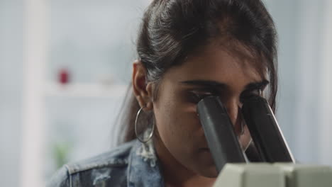 Estudiante-Indio-Ajusta-El-Microscopio-Para-Examinar-La-Muestra-De-Prueba