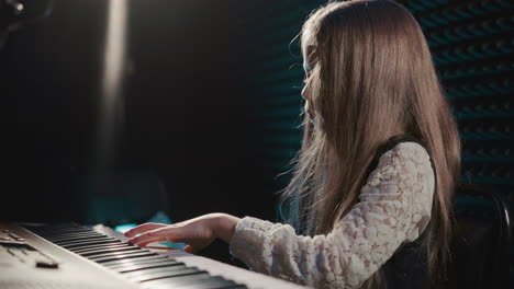 synthesizer comes alive as child plays. petite girl musician with undeniable talent performs enchanting piano melody. concentrated behavior during playing