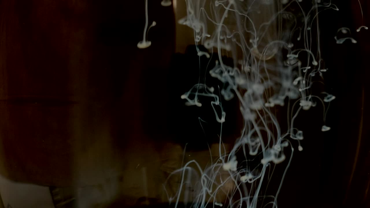 эффекты, например 4k. белая краска падает сверху, смешиваясь с водой. чернила медленно вращаются под водой. облако чернил изолировано на черном фоне.