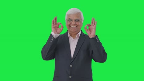 Happy-Indian-senior-manager-showing-okay-sign-Green-screen