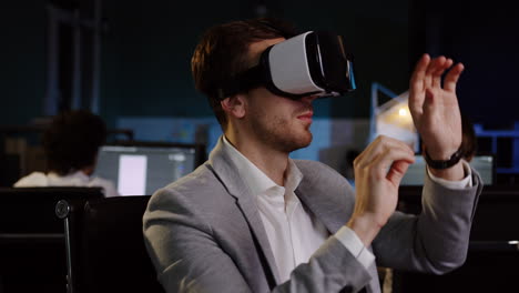 young businessman using vr glasses at his workplace late in the evening