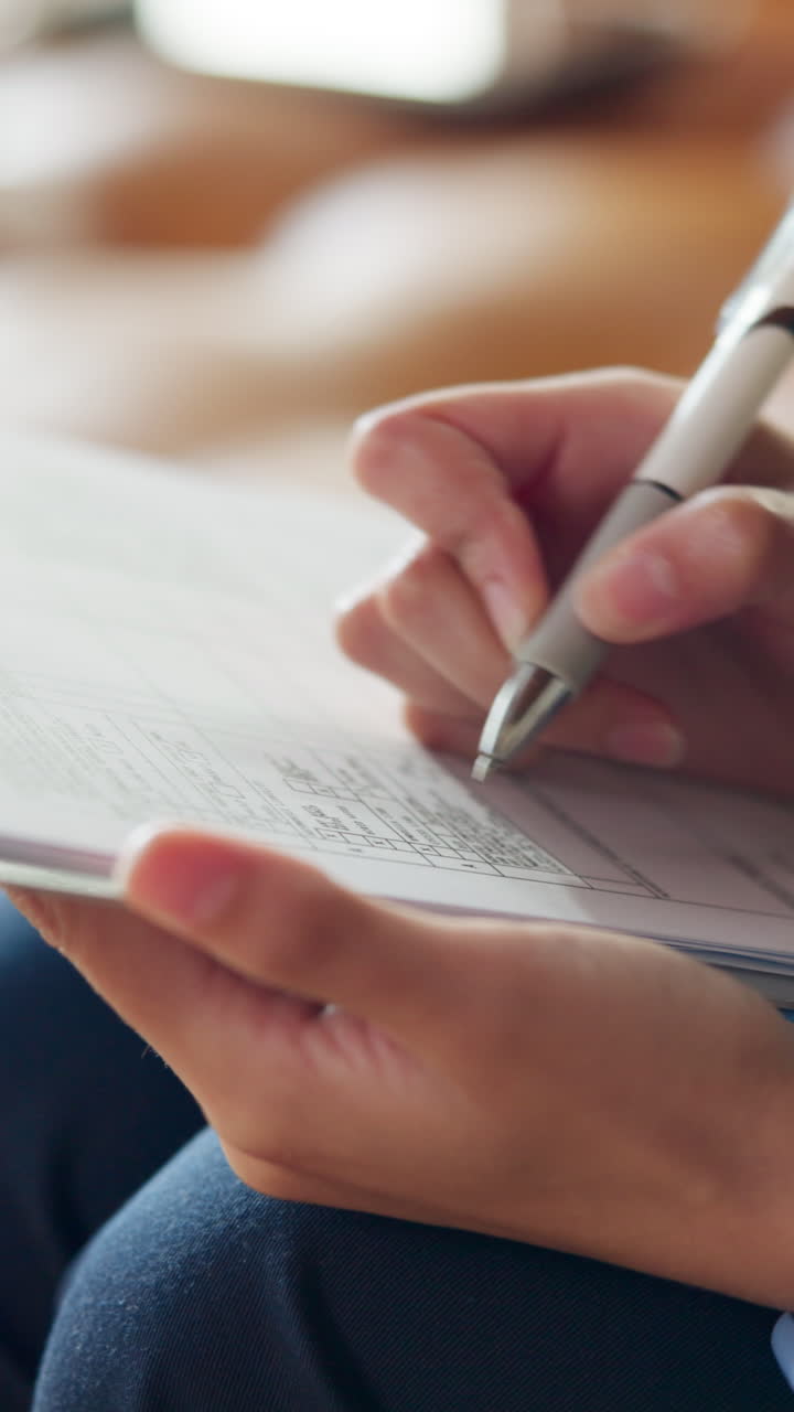 Close-up of Person's Hands Writing on a Document with a Pen