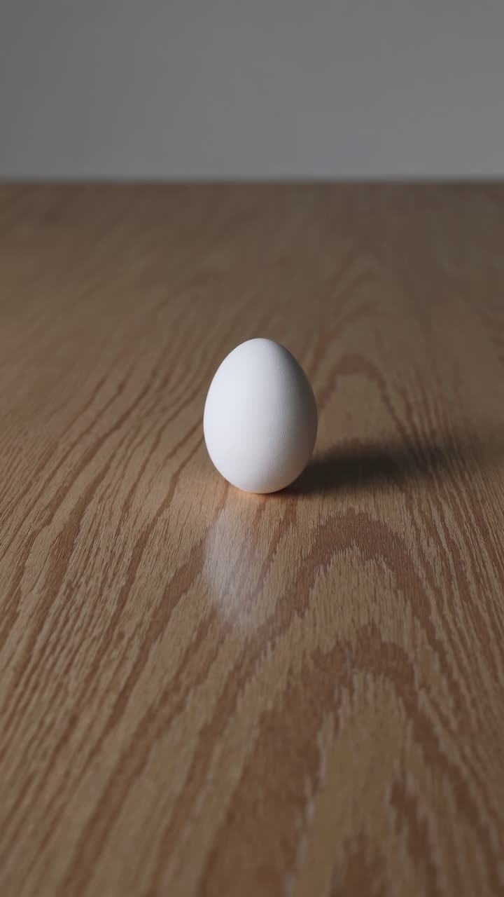 Minimalist video concept featuring a single egg on a wooden surface