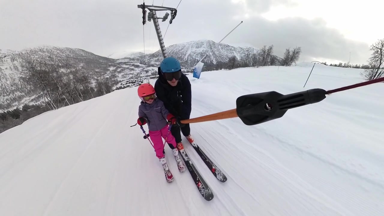 Father and young daughter using T-bar ski-lift together - Handheld stabilized
