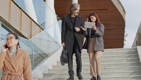 business professionals walking down stairs with mobile devices