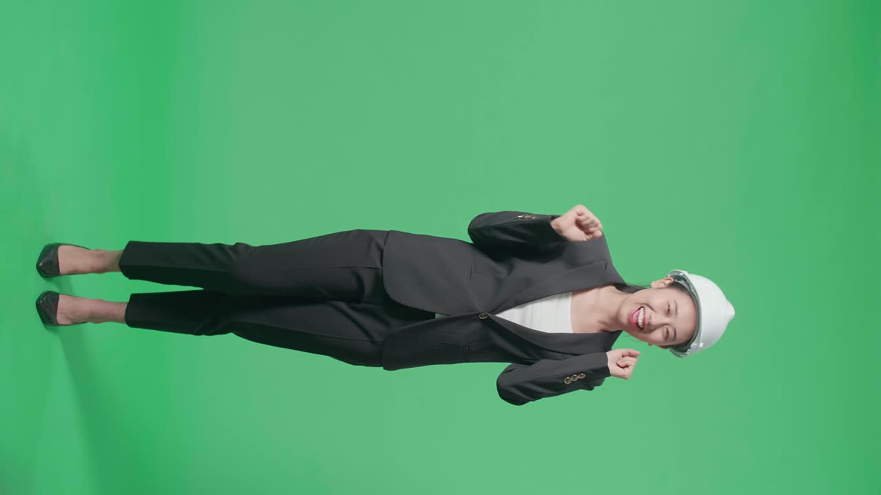 Full Body Of Smiling Asian Female Engineer With Safety Helmet Dancing In The Green Screen Studio