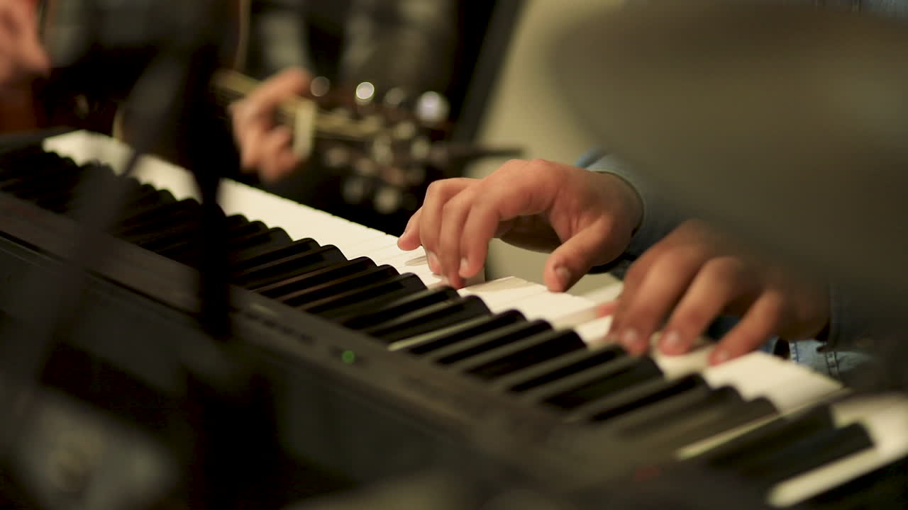 A man plays the piano with a guitarist in the studio