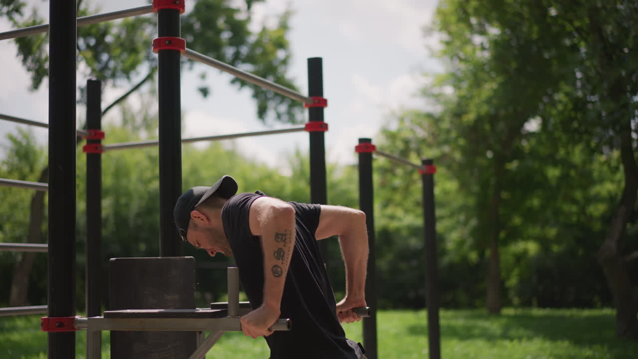 Person Exercises Outdoors, Man Engaged In Outdoor Muscle Workout, Man Trains His Triceps In Serene Park Setting, An Individual Conducts Triceps Exercises On Bars Amidst Greenery In Quiet Park