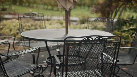 Empty-tables-with-chairs-pulled-up---summer-terrace-of-the-cafe-without-visitors