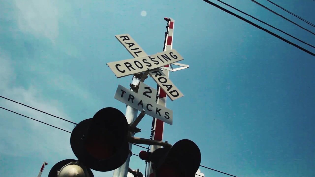 Railroad sign and power cables in front of a blue sky.