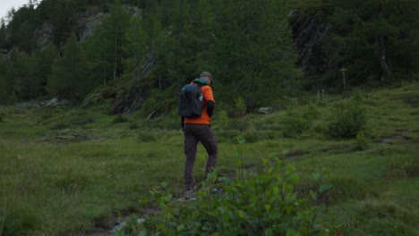 solo traveler hikes along mountain trail, pauses to take picture using phone