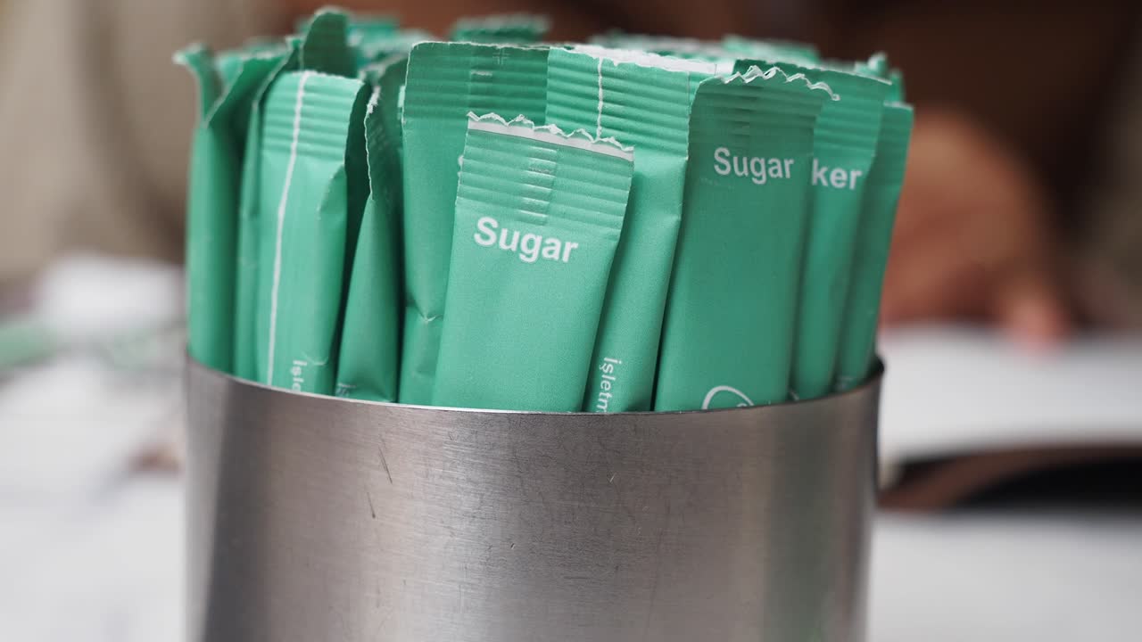 primer plano de paquetes de azúcar en un recipiente metálico