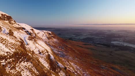 4k aerial fly by angle of campsie fells cliff face at sunset