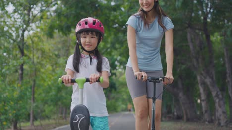 mother and daughter riding scooters in a park