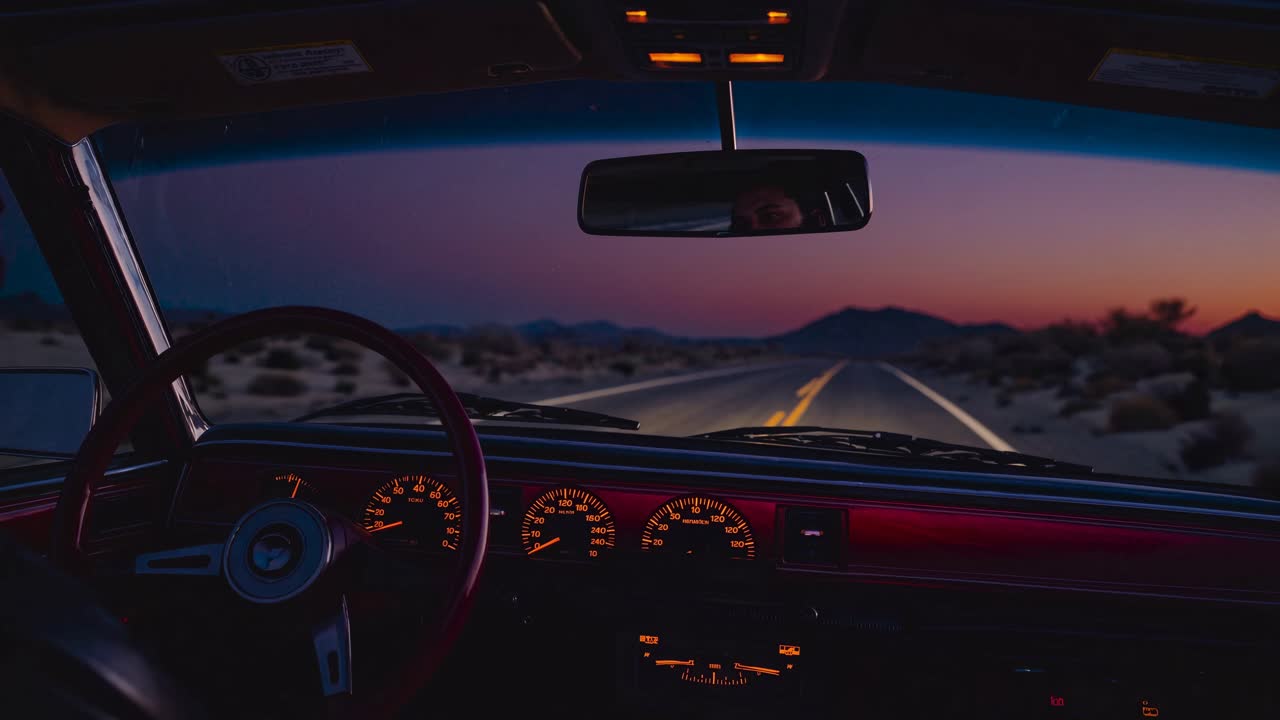 POV video style from inside a car at dusk, capturing a serene desert road view