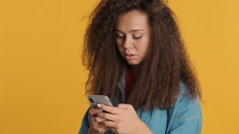 Caucasian curly haired woman using smartphone.