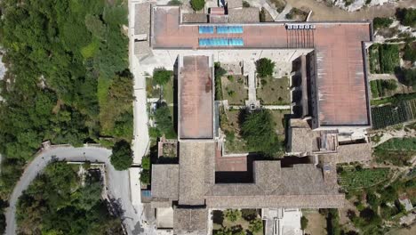 Flying-Over-The-Santuario-Santa-Maria-Scala-del-Paradiso-Surrounded-By-Green-Trees-Near-The-Old-City-Of-Noto,-Sicily,-Italy