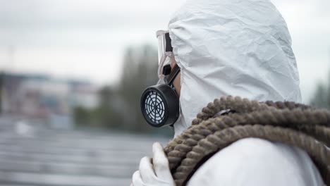 worker in protective mask and respirator outdoors standing with ropes