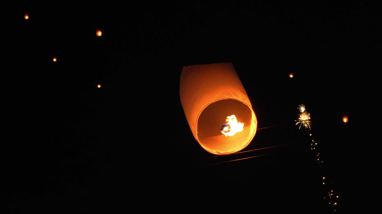 Una linterna de papel encendida queda atrapada en los cables eléctricos aéreos por la noche, lo que pone de manifiesto los posibles riesgos de incendio durante el lanzamiento de linternas.