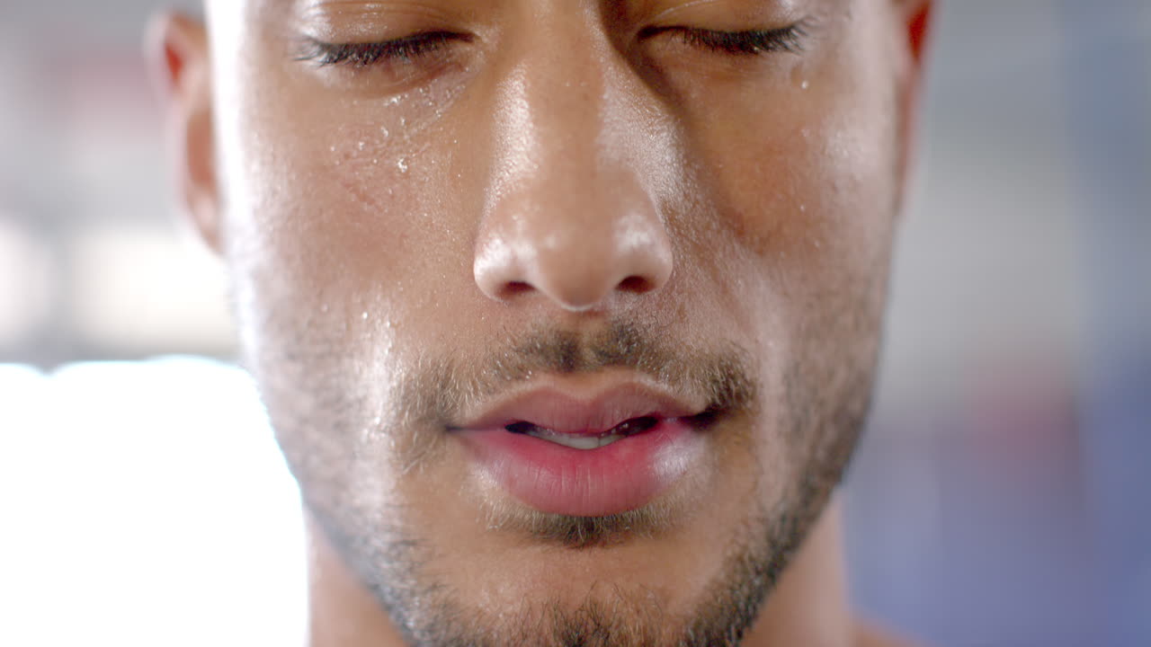 Working out intensely at gym, man sweating and focusing on exercise