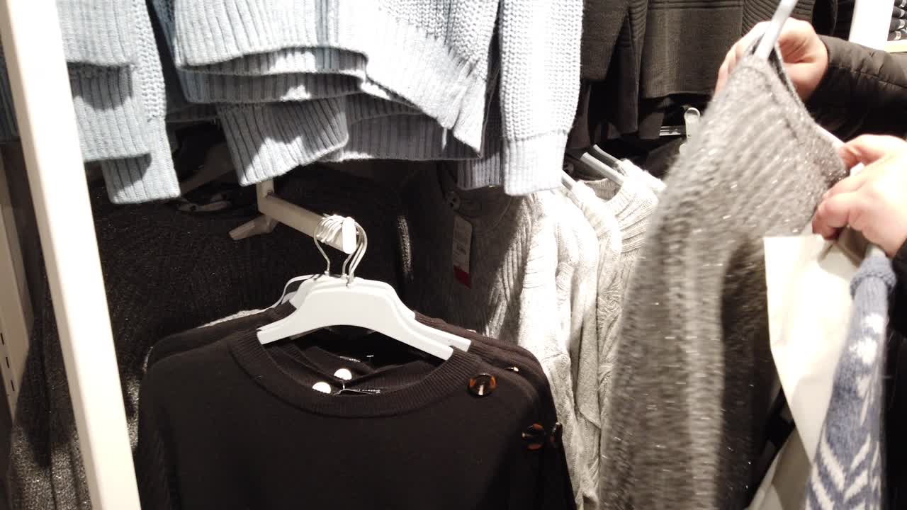The buyer chooses a sweater in the mall