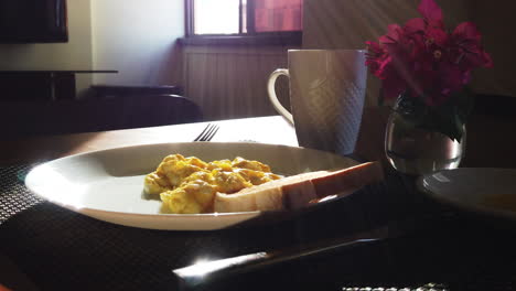 desayunos sentados en una mesa con el sol de la mañana entrando por la ventana