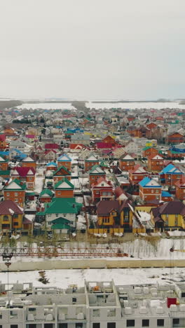 flight over residential cottage complex by gray ongoing building with yellow construction cranes on weekend