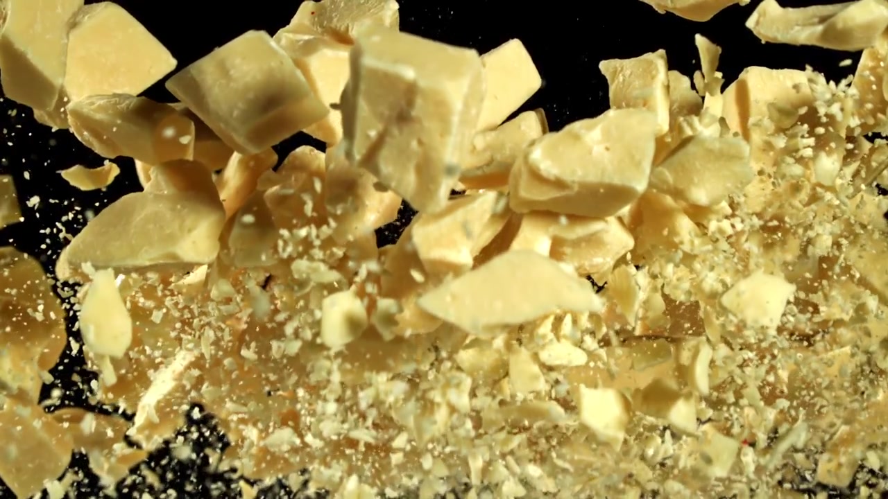 Pezzi e polvere di cioccolato bianco che esplodono in super slow motion