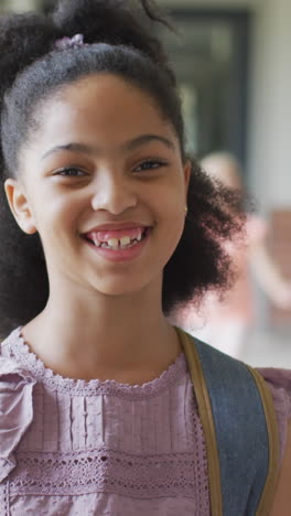 video of happy biracial girl standing at school corridor