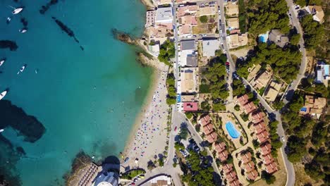 Playa-de-san-telmo,-island-of-mallorca,-with-bustling-beach-and-clear-turquoise-waters,-in-summer,-aerial-view,-Spain,-in-the-Mediterranean-Sea