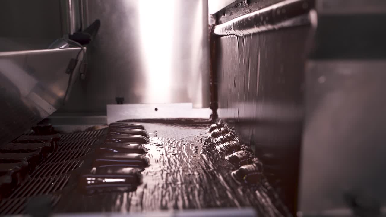 Chocolate Factory. A stream of hot melted chocolate. Candy production on an automatic line